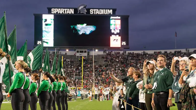 Donors on the field with video board in the background